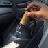 A hand holds a bamboo torch with a black end, illuminated, inside a vehicle. It features a branding logo.