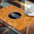 An orange place mat featuring sketches of fruits and vegetables, with a central logo.