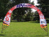 A curved arch banner measuring 3000mm x 2500mm with a red, white, and checkered design, featuring a logo.