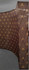 A curved promotional media wall in brown with a repeating logo pattern in gold.