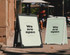 Two premium plastic water-fillable corflute A-frames in black and white, standing on a footpath with people in the background.