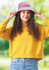 A woman wearing a pink terry towelling bucket hat and a yellow sweatshirt, with a logo on the hat.