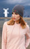 A woman wearing a grey recycled roll down beanie, paired with a light pink hoodie, in an outdoor setting.