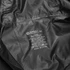 A black windbreaker made of 100% polyester, featuring care instructions and a logo.