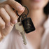 A key ring featuring a rectangular design in black, attached to a metal key, held by a person.
