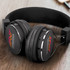 A pair of black Bluetooth headphones with a logo on the ear cups, featuring cushioned ear pads and a sleek design.
