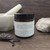 Northland Remedies Warm Vanilla Magnesium Lotion in a 4 oz amber glass jar, displayed next to an open jar of thick white topical cream, vanilla beans, lavender buds, and a white ceramic mortar and pestle on a dark wood background.