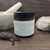 Northland Remedies Warm Vanilla Magnesium Lotion in a 4 oz amber glass jar, displayed next to an open jar of thick white topical cream, vanilla beans, lavender buds, and a white ceramic mortar and pestle on a dark wood background.