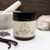 Northland Remedies Warm Vanilla Magnesium Lotion in a 4 oz amber glass jar, displayed next to an open jar of thick white topical cream, vanilla beans, lavender buds, and a white ceramic mortar and pestle on a dark wood background.