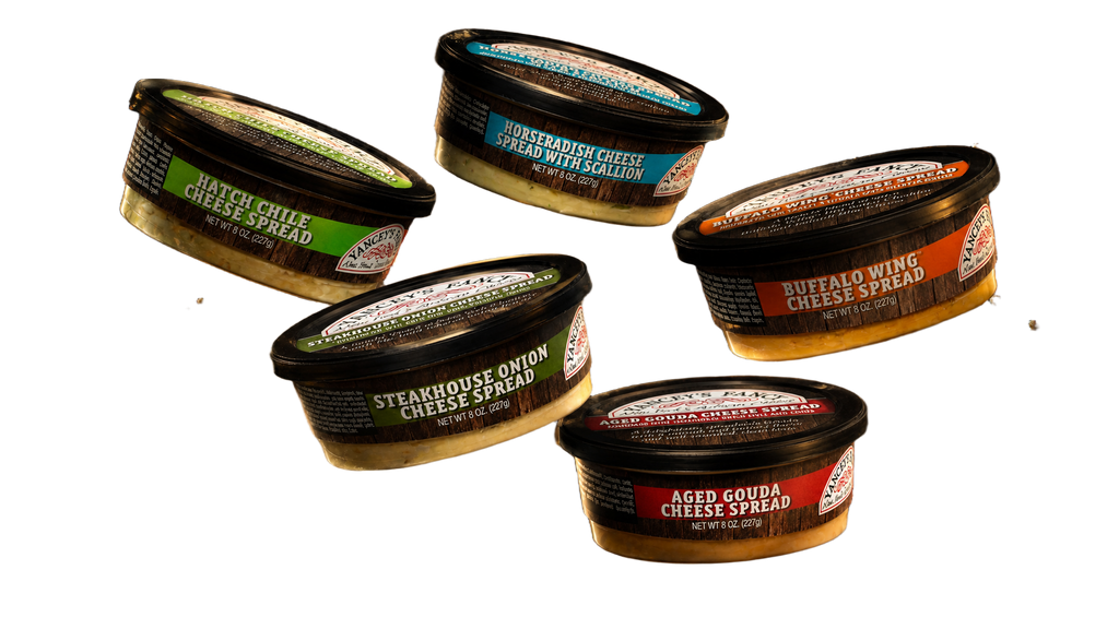 A dynamic product lineup showcasing five 8-ounce tubs of Yancey's Fancy Cheese Spreads floating at an angle against a solid light gray background. The collection features color-coded labels for Hatch Chile (light green), Horseradish with Scallion (blue), Steakhouse Onion (dark green), Buffalo Wing (orange), and Aged Gouda (red) flavors.