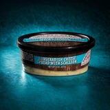 An open 8-ounce (227g) plastic tub of Yancey's Fancy Horseradish Cheese with Scallion Cheese Spread with the lid removed, revealing the textured, creamy, off-white cheese blend inside. The front label features bold white text reading "HORSERADISH CHEESE WITH SCALLION CHEESE SPREAD" on a rustic woodgrain and green background, set against a vibrant orange backdrop.