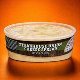 An open 8-ounce (227g) plastic tub of Yancey's Fancy Steakhouse Onion Cheese Spread with the lid removed, revealing the textured, creamy, off-white cheese blend inside. The front label features bold white text reading "STEAKHOUSE ONION CHEESE SPREAD" on a rustic woodgrain and green background, set against a vibrant orange backdrop.