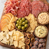 Lifestyle photo of the Grand Gathering gift box set out at a party, showing its charcuterie, cheese, and cracker spread ready for guests.