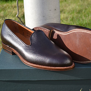 Dark leather Alden loafers displayed on a box outdoors.