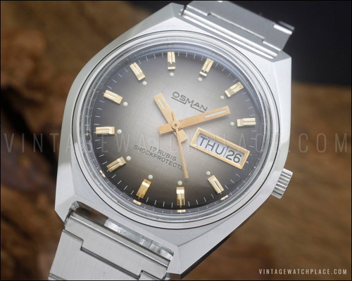 NOS Osman vintage mechanical watch in stainless steel, with brown fumé dial, day-date calendar, raised gold-tone indexes and original steel bracelet.