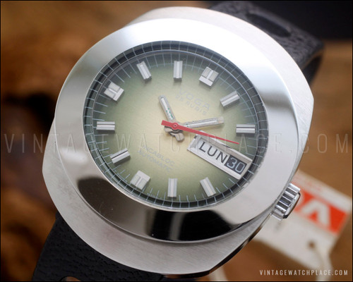 NOS Voga automatic vintage watch in stainless steel, with green fumé dial, red central seconds hand, Spanish day-date calendar and black perforated strap.