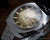 Three-quarter view of the Sakay 61365A NOS automatic watch, highlighting the faceted case, raised crystal, integrated steel bracelet and champagne-gold dial.