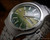 Angled view of the New Old Stock Osman 2378W3 automatic, showing the green sunburst dial, stainless steel case, original bracelet and red hang tag.