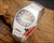 New Old Stock Osman NS6633 automatic watch displayed on wood, showing the purple-green gradient dial, stainless steel case, original bracelet and red hang tag.