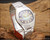 Angled view of the Osman NS6633 NOS automatic watch on wood, highlighting the faceted Plexiglas crystal, striped dial, stainless steel case and original bracelet.