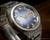 Angled close-up of the Osman-Clipper LH-1004 two-tone blue dial, highlighting the raised gold-tone indexes, hands, minute track and framed day-date window.