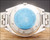 
Caseback view of the Osman-Clipper LH-1004 automatic watch, showing the all-stainless-steel back, original bracelet and blue protective sticker.