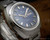 Angled close-up of the Osman two-tone blue dial, highlighting the raised silver-tone indexes, hands, minute track and framed day-date window.
