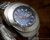 Detailed angled dial close-up of the Osman automatic watch, highlighting the blue dial, silver-tone indexes and red central seconds hand.