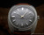 Front view of the Stelwatch automatic watch, with grey fumé dial, raised silver-tone indexes, silver-tone hands, aged luminous dots and date display.