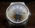 Front close-up of the Tecnal automatic watch, showing the smoky brown-grey dial, 25-ruby marking, Incabloc text, applied indexes and day-date display.