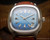 New Old Stock Tecnal automatic watch displayed on wood, with blue dial, 30-jewel movement, cushion-shaped case and brown vintage-style strap.