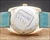 Caseback view of the Tecnal automatic watch, showing the stainless steel back, old reference sticker and turquoise leather strap.