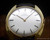 Front view of the Titus Swiss manual-winding watch with brushed silver dial, applied dark baton hour markers, two hands and gold-plated case.