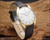 Angled view of the NOS Titus mechanical watch on wood, showing the distinctive 1970s-style case, slim two-hand dial and elegant black leather strap.