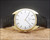 Full front display of the Titus vintage mechanical watch, showing the gold-plated case, brushed silver dial, angular lugs and black leather strap.
