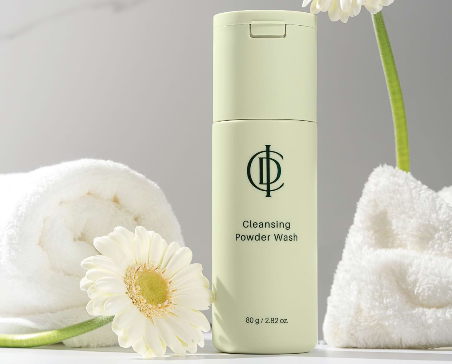 Incellderm ICD Cleansing Powder Wash lifestyle with a flower and rolled towels