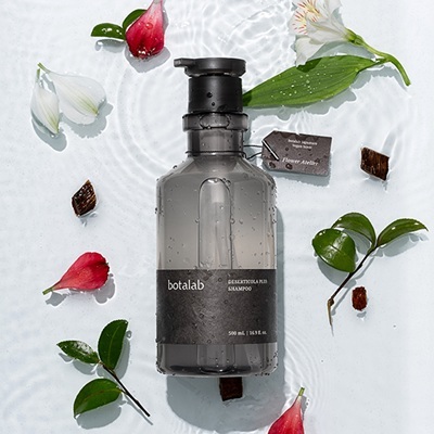 Deserticola Plus Shampoo lifestyle with flowers and petals