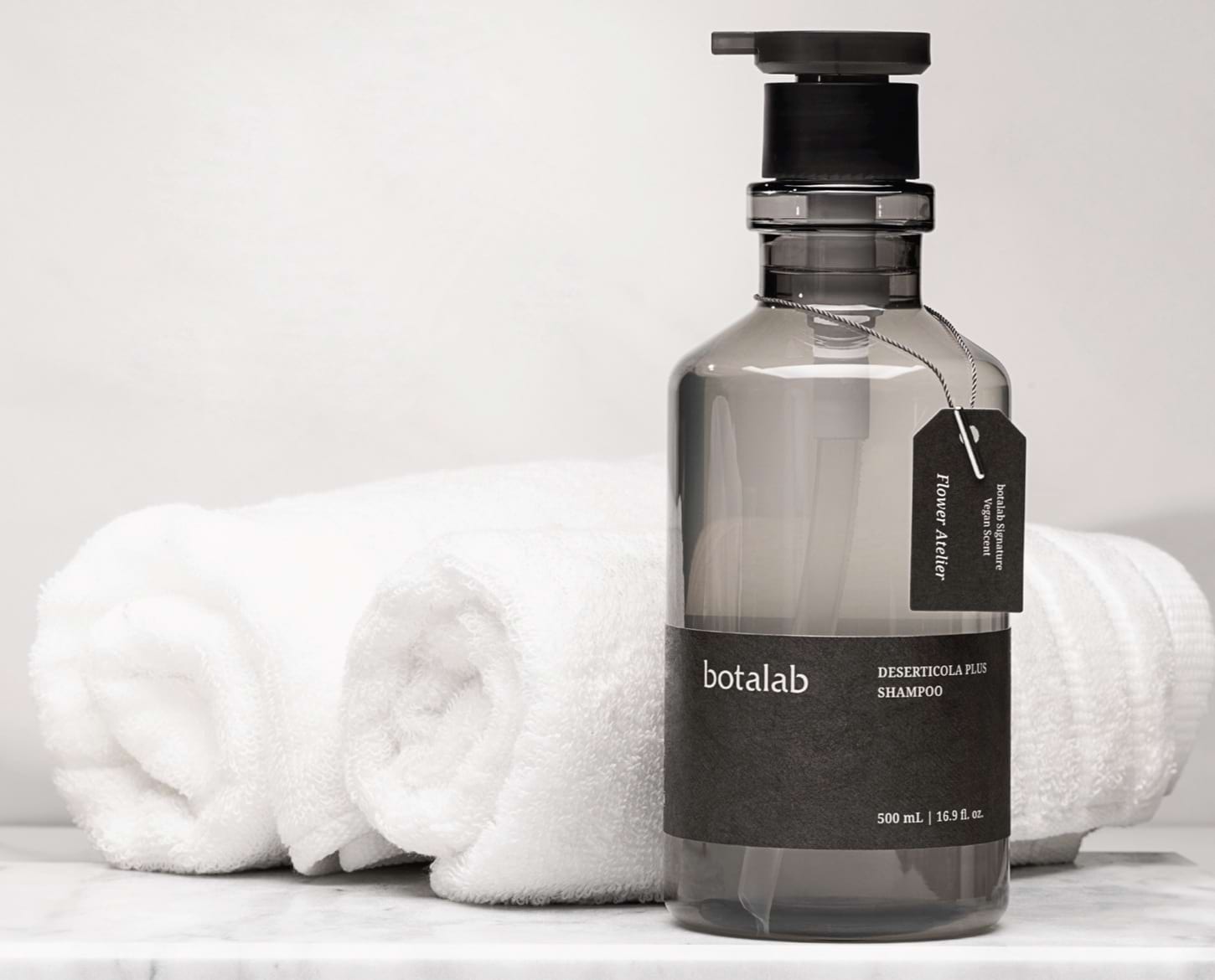 Deserticola Plus Shampoo in a bathroom with rolled towels