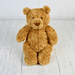 Classic brown plush Jellycat Bartholomew Bear Medium sitting upright on a white wooden background.
