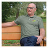 Man wearing vietnam veteran ribbons and map embroidered olive drab green polo shirt sitting on park bench