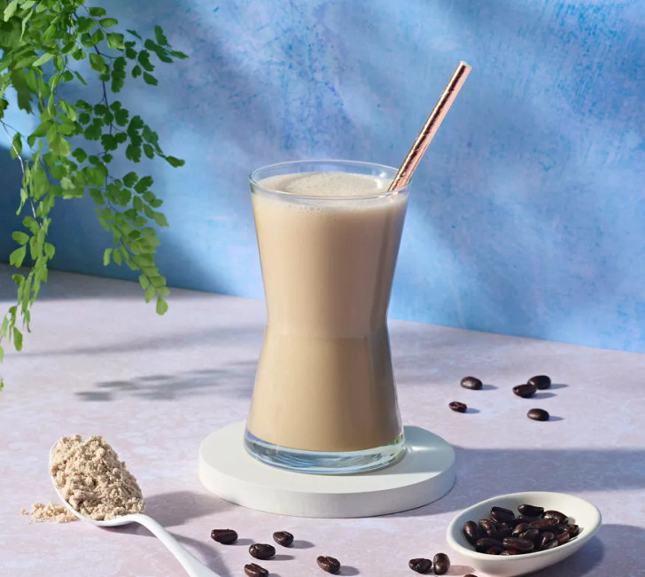 Herbalife Formula 1 Healthy Meal Nutritional Shake Mix (Café Latte) 550g in a glass with coffee beans beside.