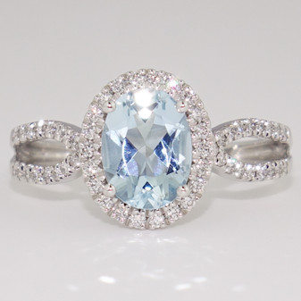 Platinum oval cut aquamarine and round brilliant cut diamond halo ring with open diamond-set shoulders