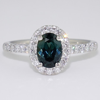Platinum oval cut teal sapphire and round brilliant cut diamond cluster ring with diamond-set shoulders