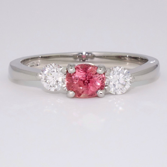 Platinum oval cut padparadscha sapphire and round brilliant cut diamond ring