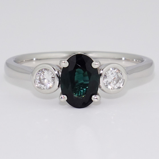 Platinum oval cut teal sapphire and round brilliant cut diamond ring with rubover settings