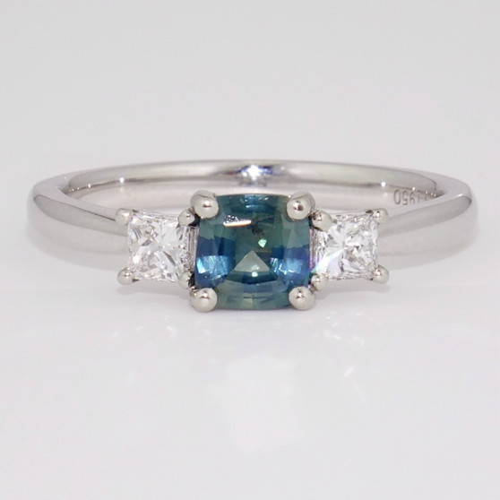 Platinum ring with opalescent cushion cut teal sapphire and two princess cut diamonds