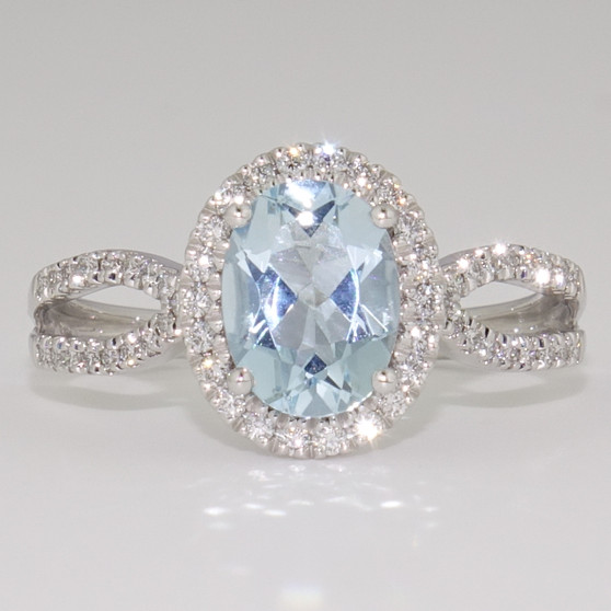 Platinum oval cut aquamarine and round brilliant cut diamond halo ring with open diamond-set shoulders