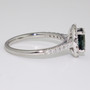 Platinum oval cut teal sapphire and round brilliant cut diamond cluster ring with diamond-set shoulders side