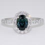Platinum oval cut teal sapphire and round brilliant cut diamond cluster ring with diamond-set shoulders
