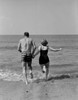 Young couple holding hands and running into sea Poster Print - Item # VARSAL255422130